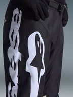 Alpinestars 2026 Racer Air Riway Pants, calças de motocross, pretas e brancas, pormenor com branding Alpinestars grande em branco, perfurações cortadas a laser para fluxo de ar e fivela de cintura ajustável, tecido durável para condução off-road