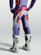 Alpinestars Supertech Dyna, calças de motocross para homem, roxo e violeta com detalhes rosa fluo, vista traseira em modelo, construção em tecido elástico respirável para alto desempenho
