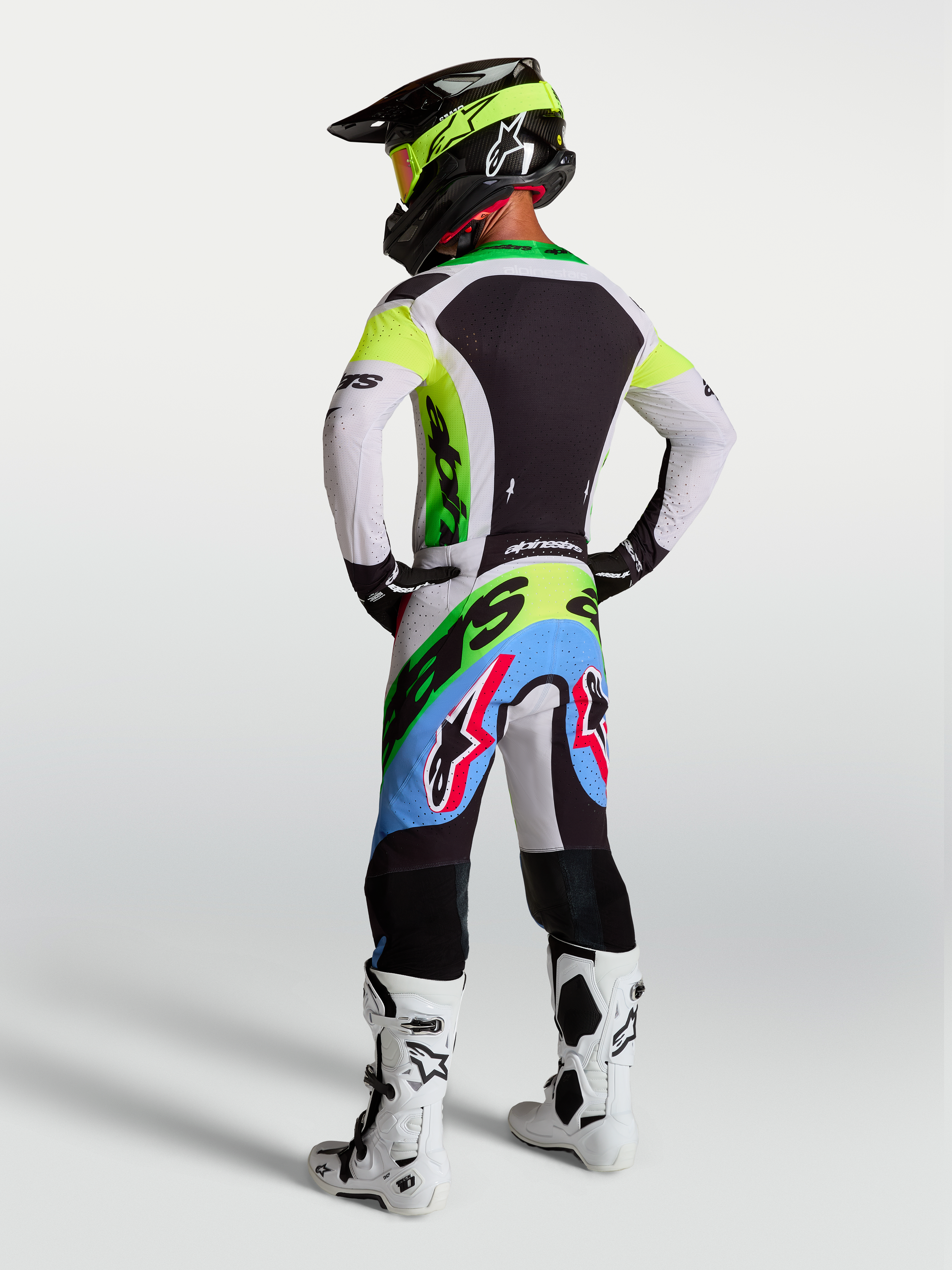Alpinestars Supertech Dyna, equipamento de motocross verde fluo, preto e lilás claro, com calças e camisola, vista traseira.