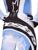 Alpinestars 2025 Techstar Melt Pants, calças de motocross, em preto, branco e azul, vista traseira em grande plano com logótipo branco em destaque no assento, combinadas com camisola e luvas Techstar Melt a condizer, equipamento de corrida profissional para motocross