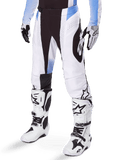 Alpinestars 2025 Techstar Melt Pants, calças de motocross, brancas e pretas com detalhes azuis, com perfurações a laser para ventilação e construção de joelho Babel, usadas com botas e luvas de motocross brancas a condizer, design atlético de corrida todo-o-terreno