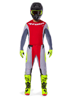 Motocross rider wearing Alpinestars 2025 Techstar Melt Pants in Bright Red and Gray, featuring vibrant red panels and fluorescent yellow accents, paired with a matching jersey, black helmet with fluorescent yellow goggles, and bright yellow boots and gloves, coordinated outfit for professional motocross racing.
