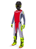 Motocross rider wearing the Alpinestars 2025 Techstar Melt Gear Set, red and gray jersey and pants, vibrant neon yellow gloves and boots, black helmet, complete off-road racing kit