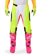 Alpinestars 2025 Techstar Melt Pants, calças de motocross, amarelo néon e branco com detalhes laranja, acompanhadas por luvas amarelas e botas de motocross cor-de-rosa vibrante, com painéis de ventilação perfurados e fivela magnética na cintura, equipamento de corrida de alta performance.