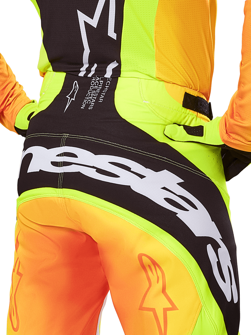Alpinestars 2025 Techstar Melt Pants, calças de motocross, pormenor da vista traseira, amarelo néon e laranja com painéis pretos, logótipo Alpinestars grande a branco na zona do assento, equipamento de condução off-road de alta performance