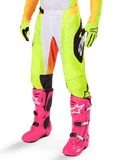 Alpinestars 2025 Techstar Melt Pants, calças de motocross, amarelo néon com detalhes brancos e laranja, padrões laterais pretos, usadas com botas de motocross cor-de-rosa vibrante e luvas amarelo néon, com perfurações para ventilação, equipamento de motocross durável