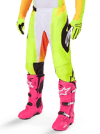 Alpinestars 2025 Techstar Melt Pants, calças de motocross, amarelo néon com detalhes brancos e laranja, padrões laterais pretos, usadas com botas de motocross cor-de-rosa vibrante e luvas amarelo néon, com perfurações para ventilação, equipamento de motocross durável