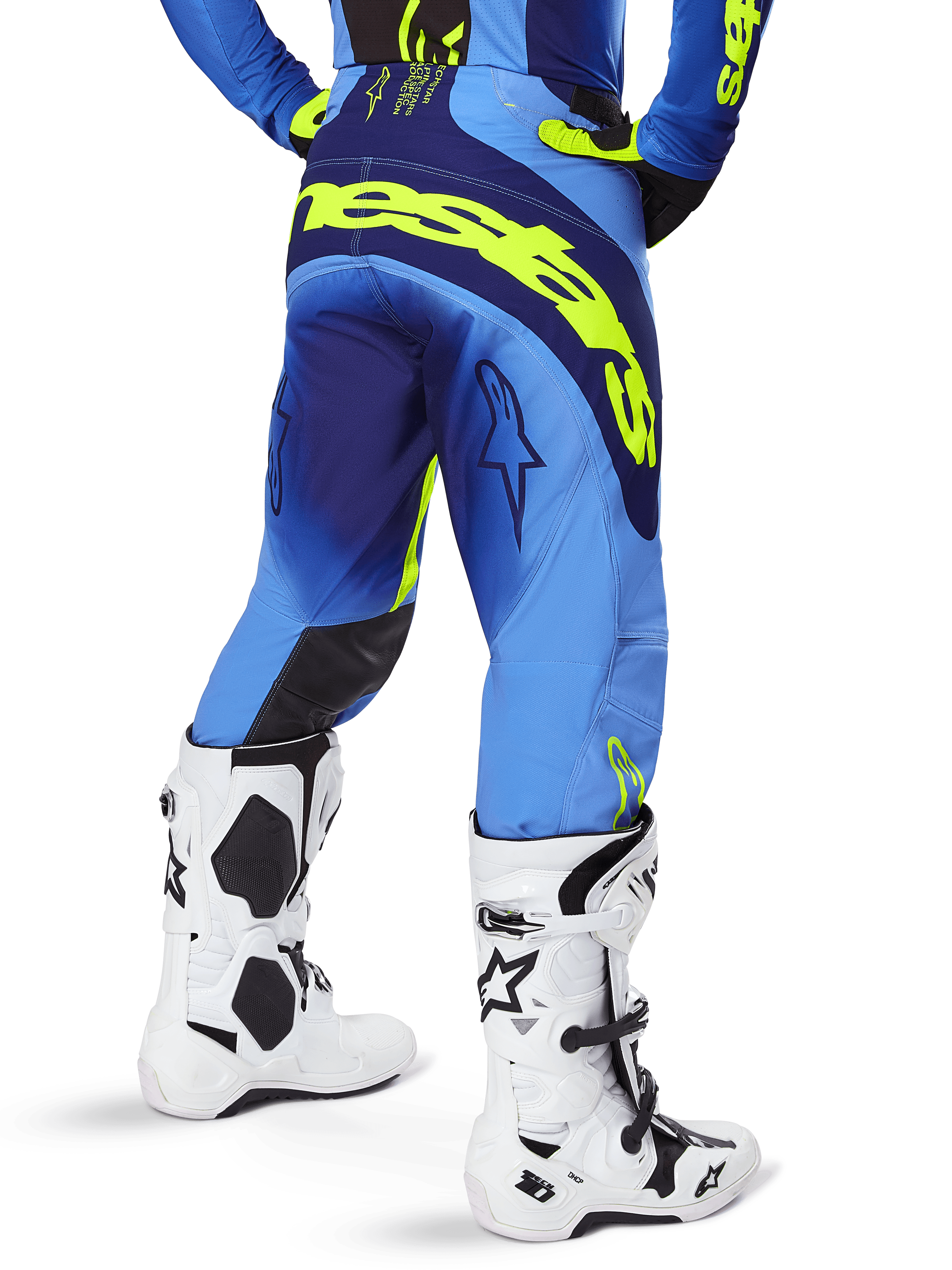 Calças Alpinestars 2025 Techstar Melt, calças de motocross, azuis e amarelo fluo, vista traseira mostrando a marca amarela grande no assento e nas coxas, usadas com botas de motocross brancas e camisola azul a condizer, corte atlético de corrida para condução todo-o-terreno