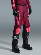 Alpinestars 2026 Racer Riway Pants, calças de motocross, Dark Red Coral, com grandes logótipos de estrela cor-de-rosa e painéis internos nos joelhos em preto, combinadas com botas de motocross pretas e luvas pretas, corte atlético de corrida para condução off-road
