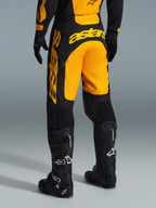 Calças Alpinestars 2026 Racer Riway, calças de motocross, amarelas e pretas, vista traseira mostrando a marca astars em destaque a amarelo no assento e na perna, combinadas com botas e luvas de motocross pretas