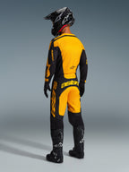 Vista traseira de um piloto de motocross equipado com as Calças Alpinestars 2026 Racer Riway em amarelo e preto, camisola a condizer, capacete preto e botas pretas, conjunto de equipamento coordenado para desempenho em todo-o-terreno