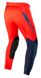 Calças Alpinestars Supertech Blaze, calças de motocross, vermelho brilhante e azul escuro, vista traseira de três quartos, logótipo ASTARS em azul escuro na lateral, painéis reforçados nos joelhos em preto, corte atlético para performance em todo-o-terreno