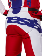 Alpinestars 2025 Racer Veil Pants, calças de motocross, vermelho vivo e branco com logótipos em azul, detalhe da vista traseira na zona do assento com um logótipo Alpinestars grande, usadas como parte de um conjunto coordenado de corrida off-road