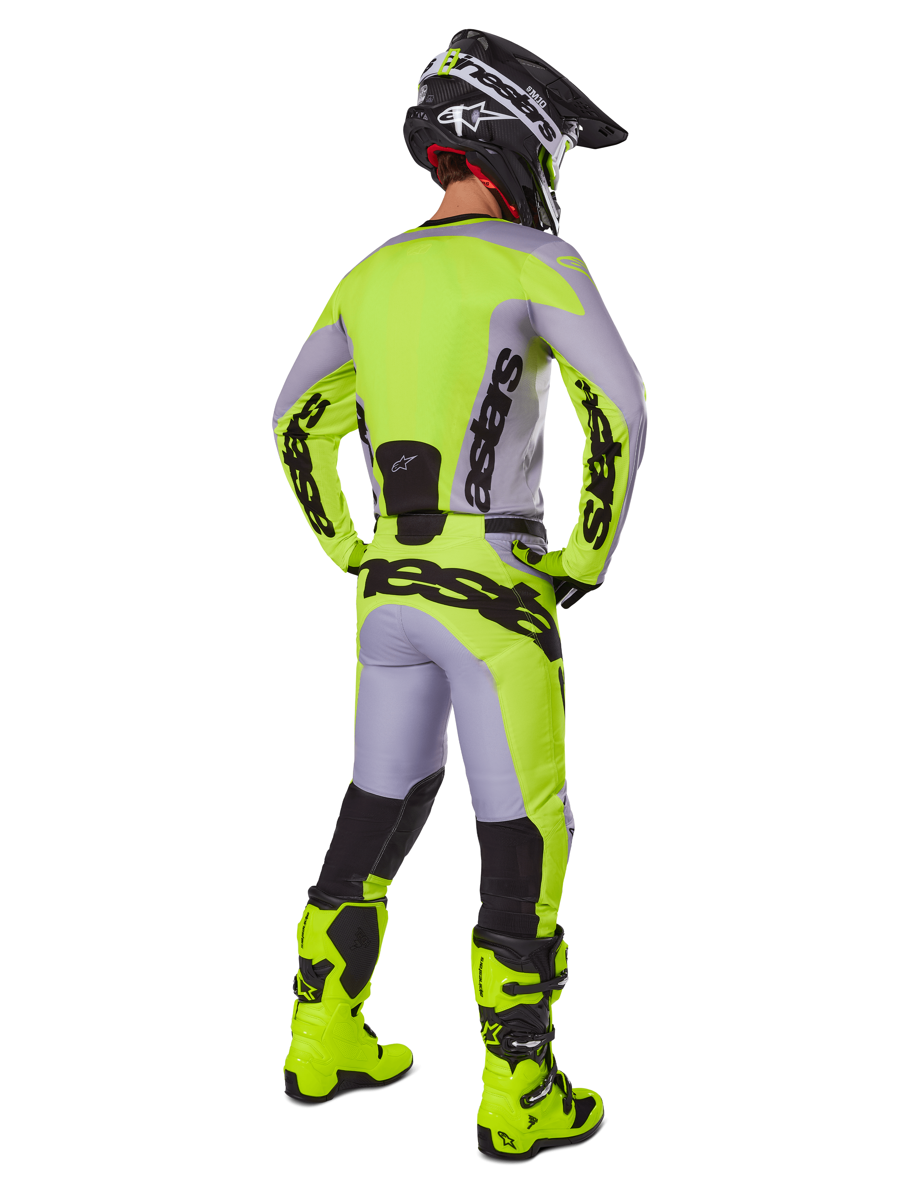 Alpinestars 2025 Racer Veil Pants, calças de motocross, cinzentas e amarelo fluorescente, vista traseira de piloto com equipamento completo, camisola a condizer e botas amarelo néon, com logótipos pretos destacados, kit técnico de corrida para todo-o-terreno