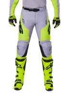 Alpinestars 2025 Racer Veil Pants, calças de motocross, cinzentas e amarelo néon, usadas com botas e luvas amarelo néon a condizer, com logótipos Alpinestars pretos, design ergonómico para corridas todo-o-terreno