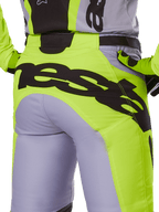 Alpinestars 2025 Racer Veil Pants, calças de motocross, cinzentas e amarelo néon, vista traseira com logótipo preto grande na zona do assento, usadas com camisola e luvas a condizer, design técnico para todo-o-terreno