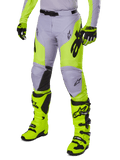 Alpinestars 2025 Racer Veil Pants, calças de motocross, cinzento e amarelo néon fluo, com logótipos de estrela pretos e cinto de cintura ajustável, apresentadas com botas e luvas de motocross a combinar, design ergonómico para condução todo-o-terreno