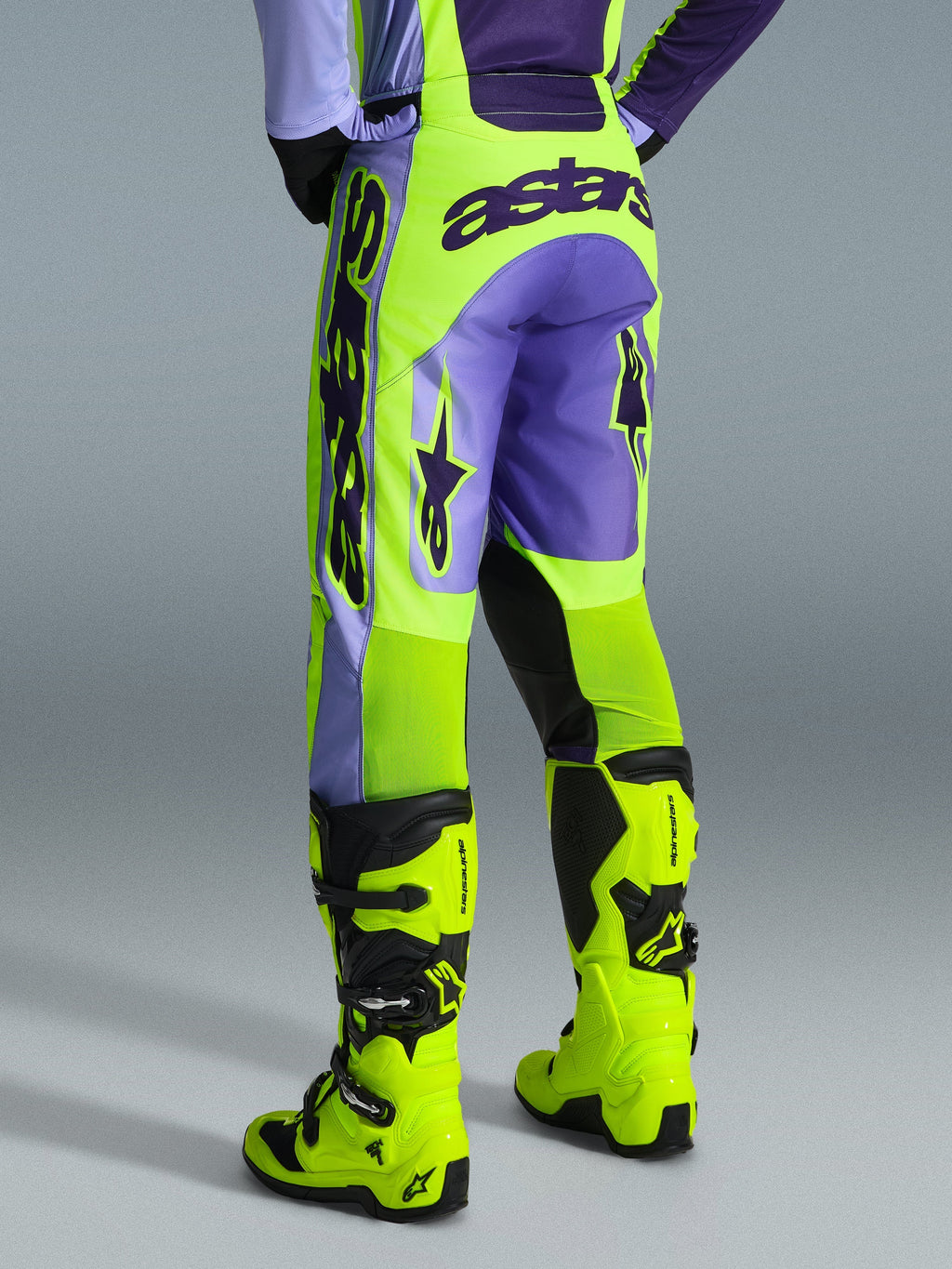 Alpinestars 2026 Racer Portl Pants, calças de motocross, roxo e amarelo néon, vista traseira com a marca astars em destaque e detalhes em roxo, usadas com botas de motocross em amarelo néon a condizer, material sintético durável para corridas fora de estrada