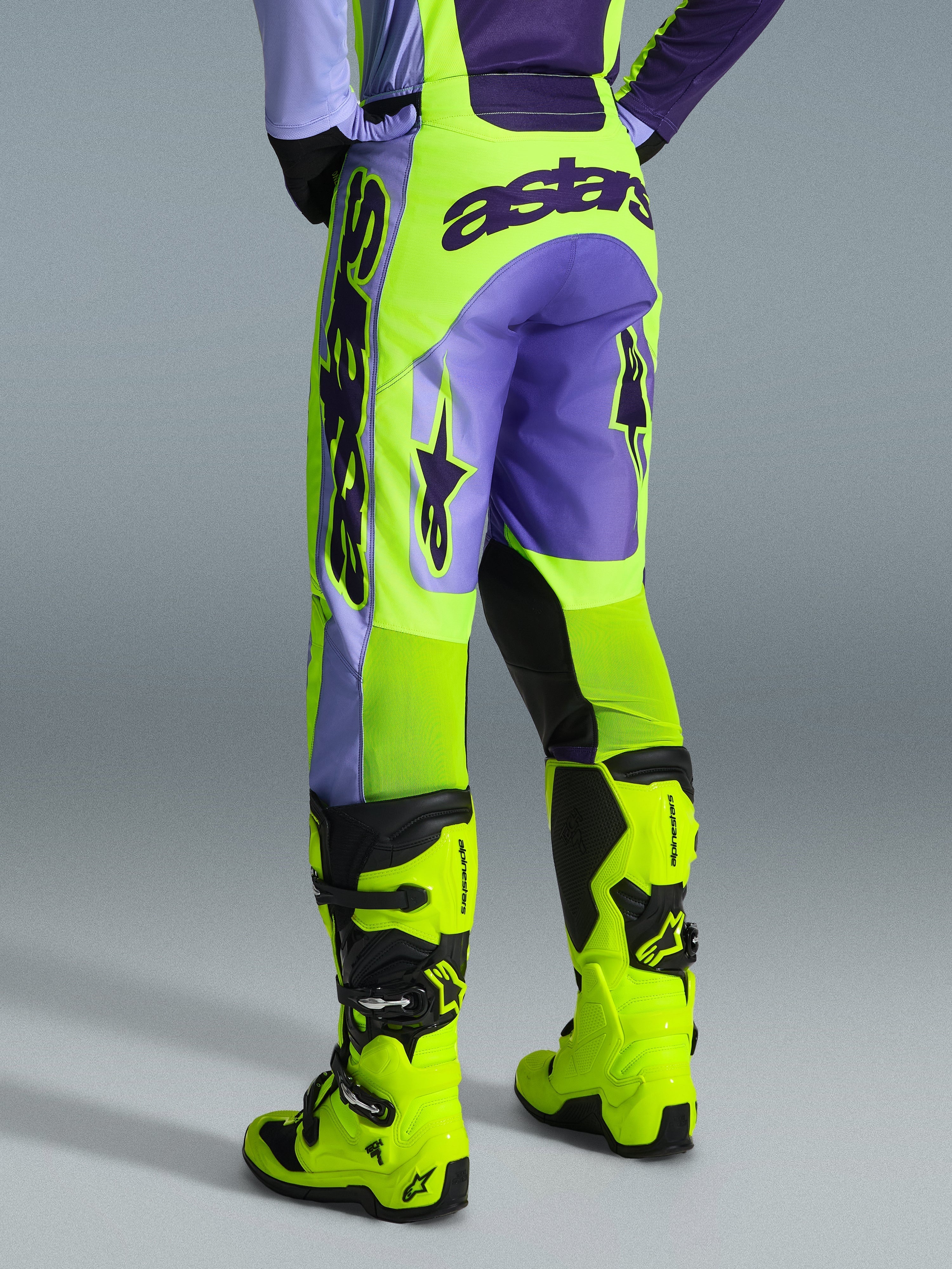 Alpinestars 2026 Racer Portl Pants, calças de motocross, roxo e amarelo néon, vista traseira com a marca astars em destaque e detalhes em roxo, usadas com botas de motocross em amarelo néon a condizer, material sintético durável para corridas fora de estrada