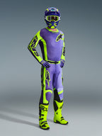 Piloto de motocross com equipamento Alpinestars 2026 Racer Portl, camisola e calças roxas e amarelo néon, botas amarelo néon, luvas roxas e capacete a condizer, conjunto coordenado de corpo inteiro para performance de motocross off-road.