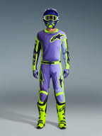 Calças Alpinestars 2026 Racer Portl e conjunto de equipamento a condizer, piloto de motocross em roxo e amarelo fluo, com camisola, capacete, óculos e botas amarelas vibrantes coordenados, concebido para desempenho off-road.
