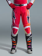 Alpinestars 2026 Racer Portl Pants, calças de motocross, vermelho, cinzento claro e cinzento escuro, usadas com luvas vermelhas a condizer e botas multicor, com logótipos de estrela Alpinestars destacados nas coxas e detalhes brancos, design desportivo para corridas off-road