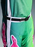 Alpinestars 2026 Racer Portl Pants, calças de motocross, verdes, brancas e pretas com detalhes do logótipo em cor-de-rosa, grande plano da cintura a mostrar a fivela magnética SX2 e o fecho ajustável, equipamento durável para corridas off-road