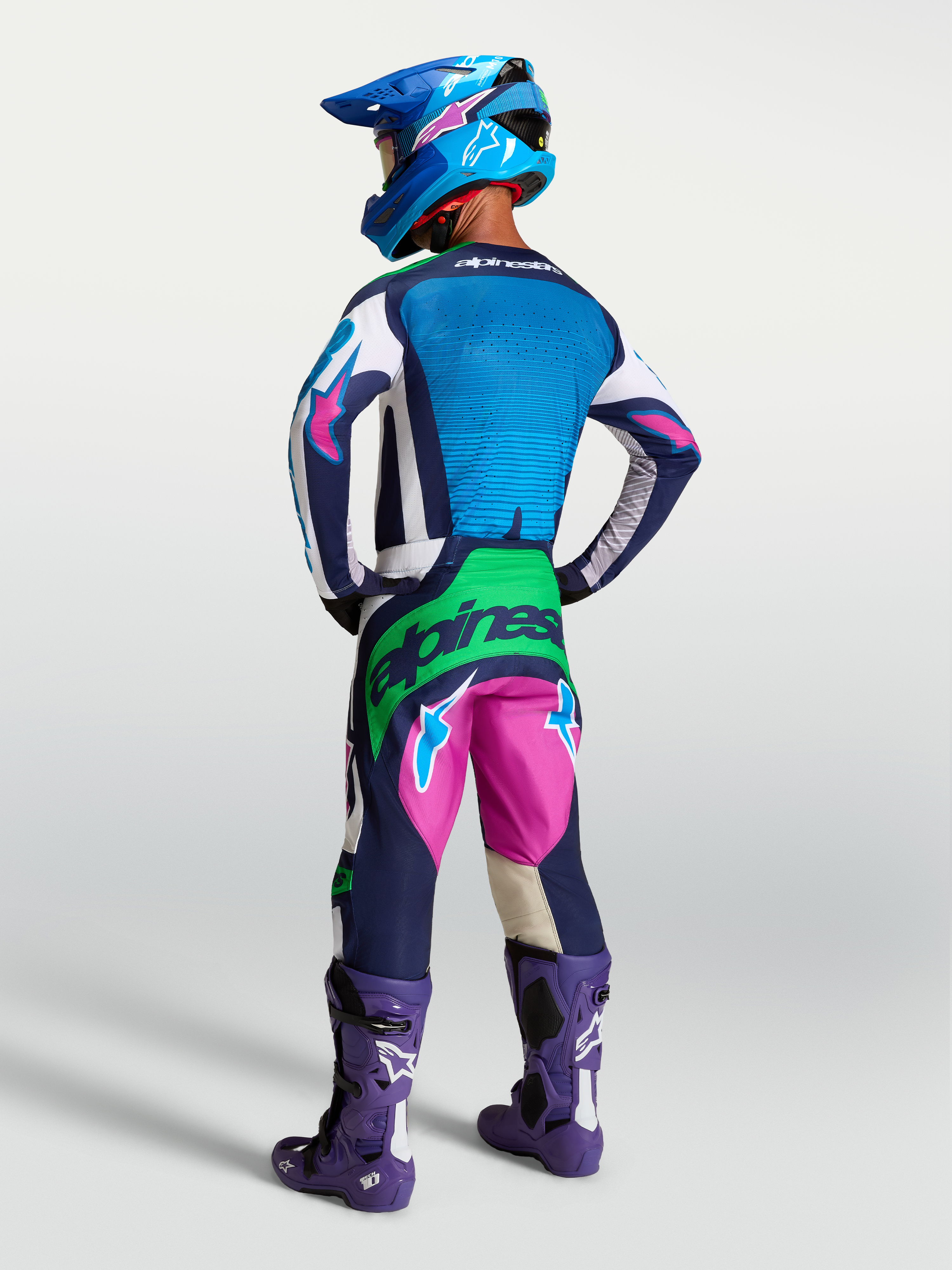 Alpinestars Techstar Maven Gear Set, conjunto de motocross azul e rosa com detalhes verde fluo, vista traseira em modelo.