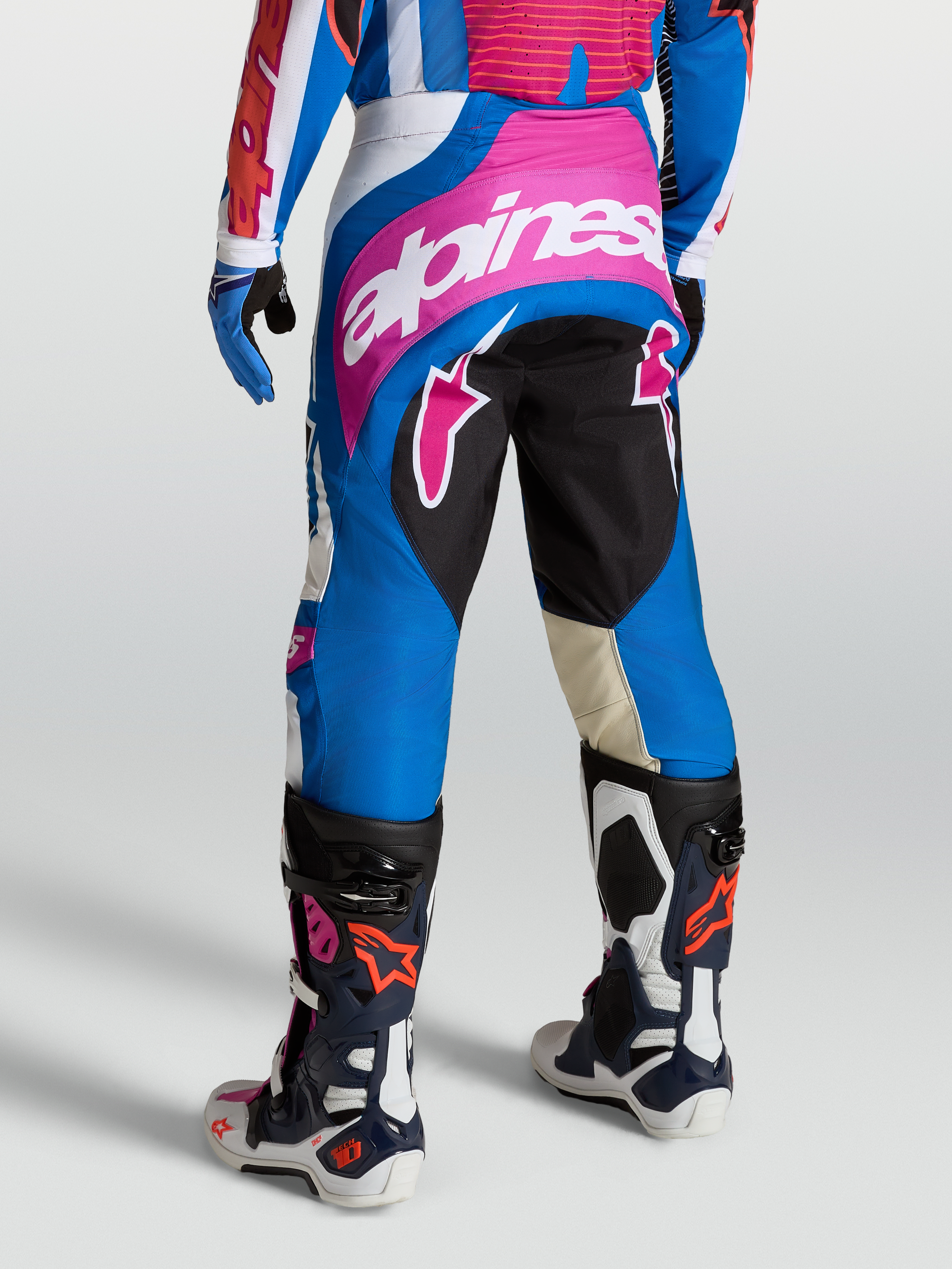 Alpinestars Techstar Maven, calças de motocross para homem, azuis e cor-de-rosa, vista traseira, com ganchos Babel e painéis elásticos, equipamento de corrida todo-o-terreno