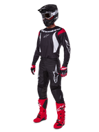 Motocross rider wearing complete Alpinestars 2025 Fluid Haul Gear Set, Black jersey with red and white accents, black pants with white logos, bright red boots, red and black gloves, black helmet with goggles, coordinated off-road performance gear