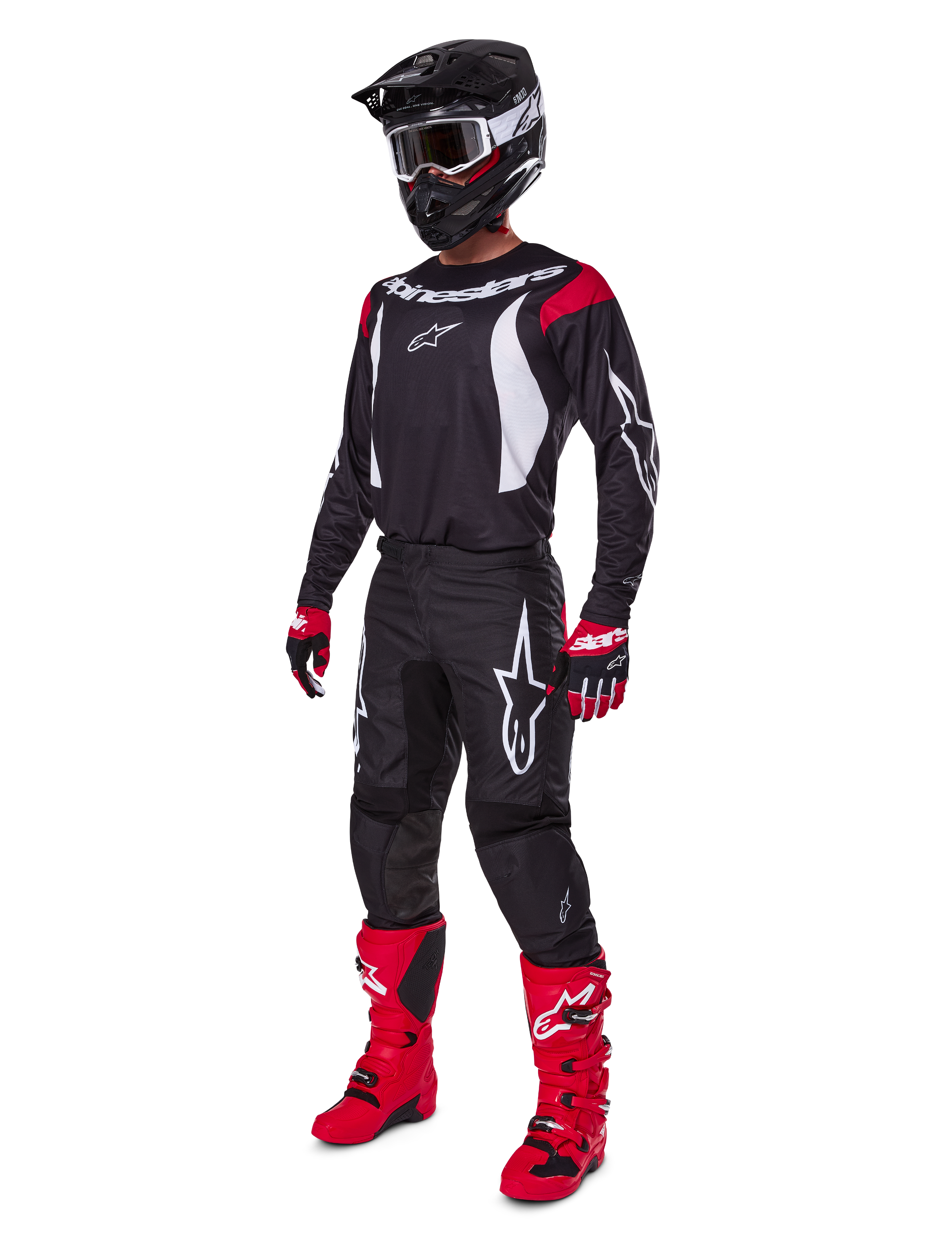 Motocross rider wearing complete Alpinestars 2025 Fluid Haul Gear Set, Black jersey with red and white accents, black pants with white logos, bright red boots, red and black gloves, black helmet with goggles, coordinated off-road performance gear