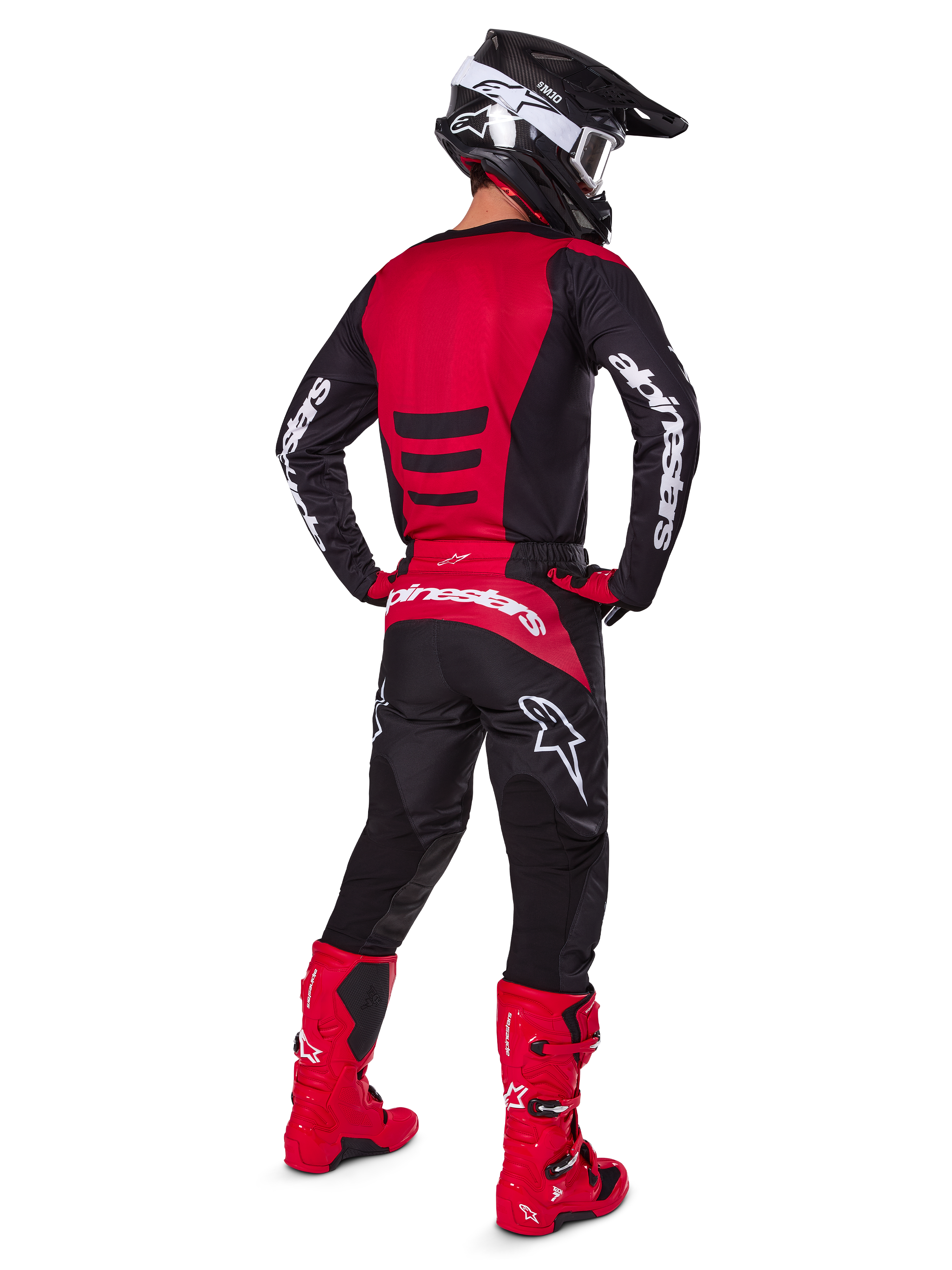 Motocross rider wearing the Alpinestars 2025 Fluid Haul Gear Set from a rear view, Red and Black jersey with white branding, matching black pants with red accents, bright red boots and black helmet with white goggles, complete coordinated outfit for off-road racing