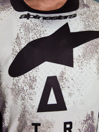 Alpinestars 2026 Racer Lahnd Jersey, camisola de motocross, padrão sarapintado em branco e cinzento, grande plano do peito com logótipo Astars preto de grandes dimensões e marca Alpinestars no decote, design orientado para a performance para condução todo-o-terreno