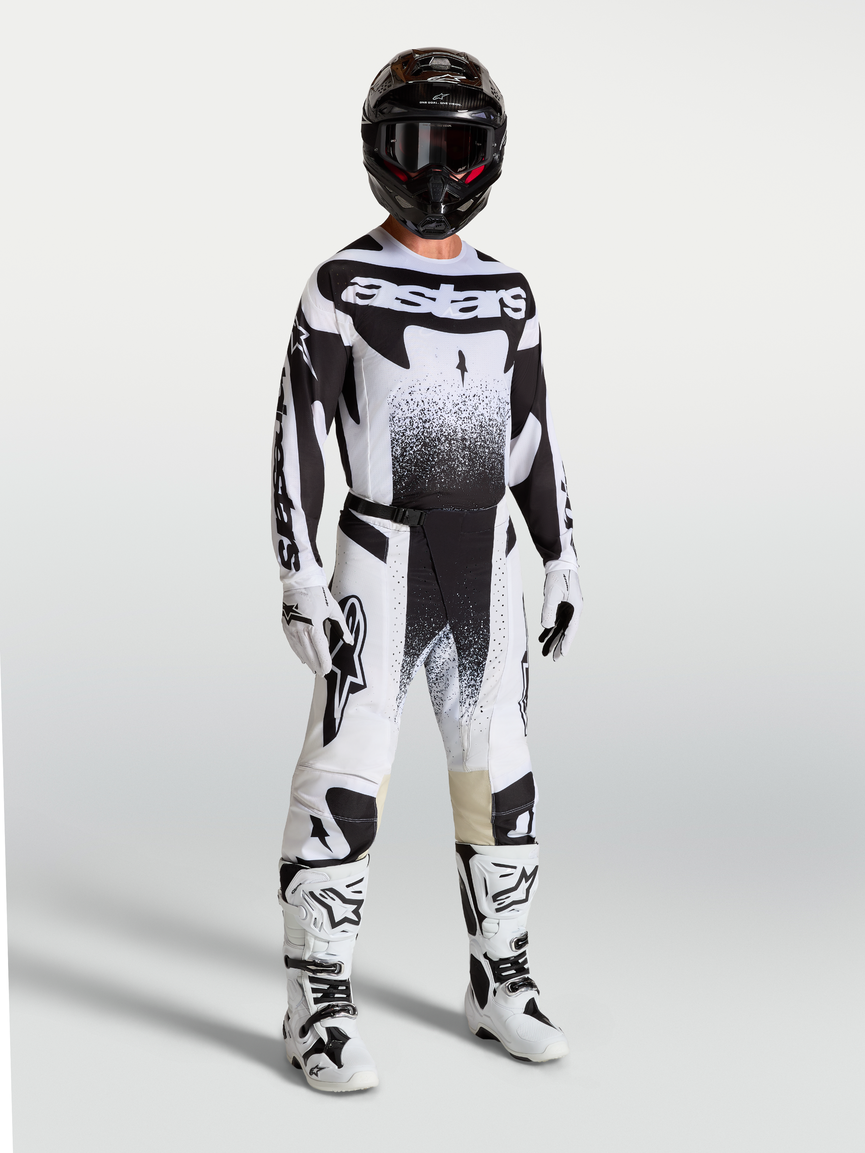 Calças Techstar Swan da Alpinestars, calças de motocross para homem, pretas e brancas, com ajuste atlético e tecido ripstop elástico, modelo vestido com equipamento de todo-o-terreno.