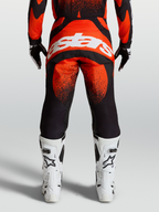 Alpinestars Calças Techstar Swan, calças de motocross para homem, vermelhas e pretas, vista traseira com logótipo branco e botas de corrida