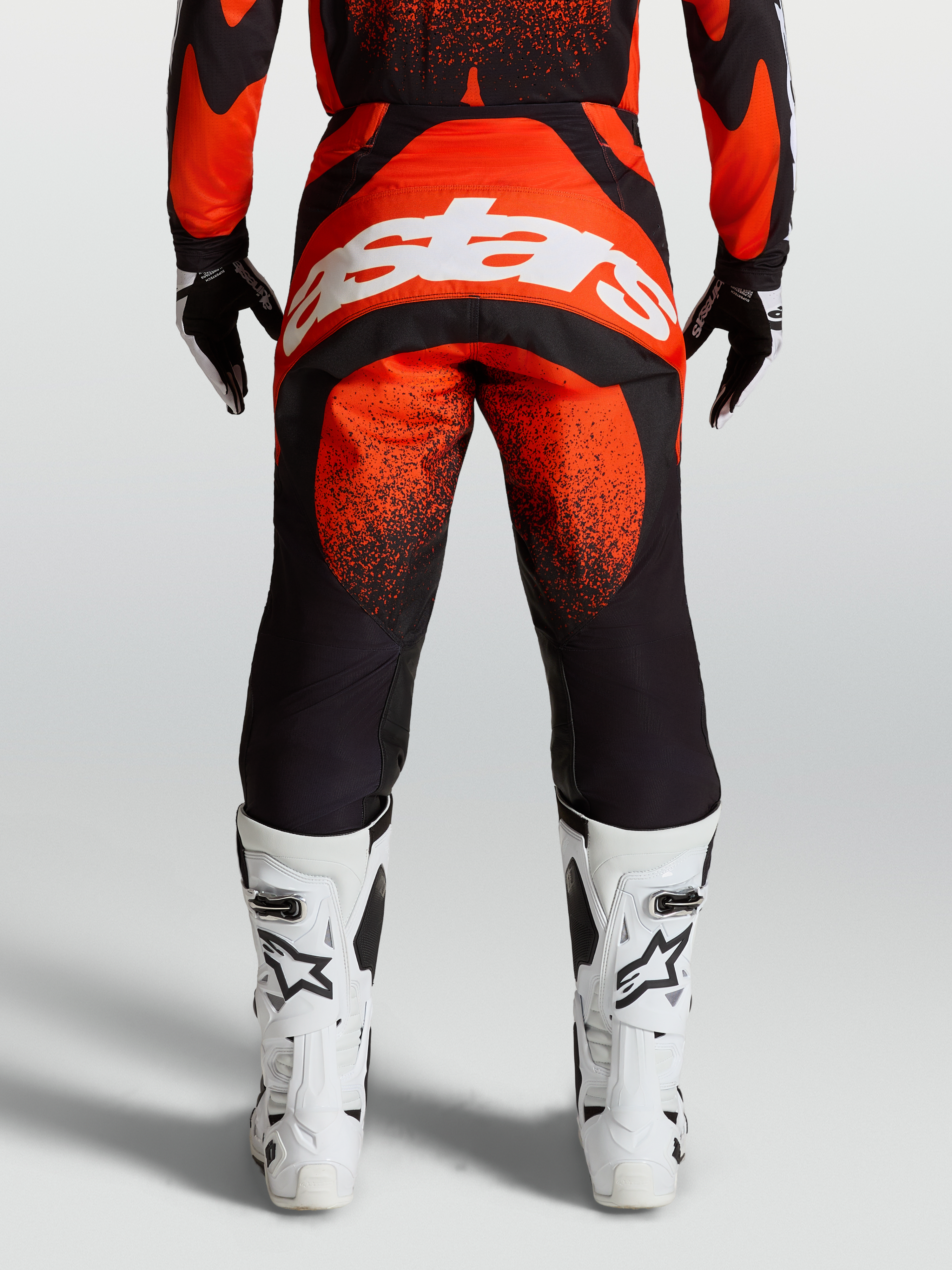 Alpinestars Calças Techstar Swan, calças de motocross para homem, vermelhas e pretas, vista traseira com logótipo branco e botas de corrida