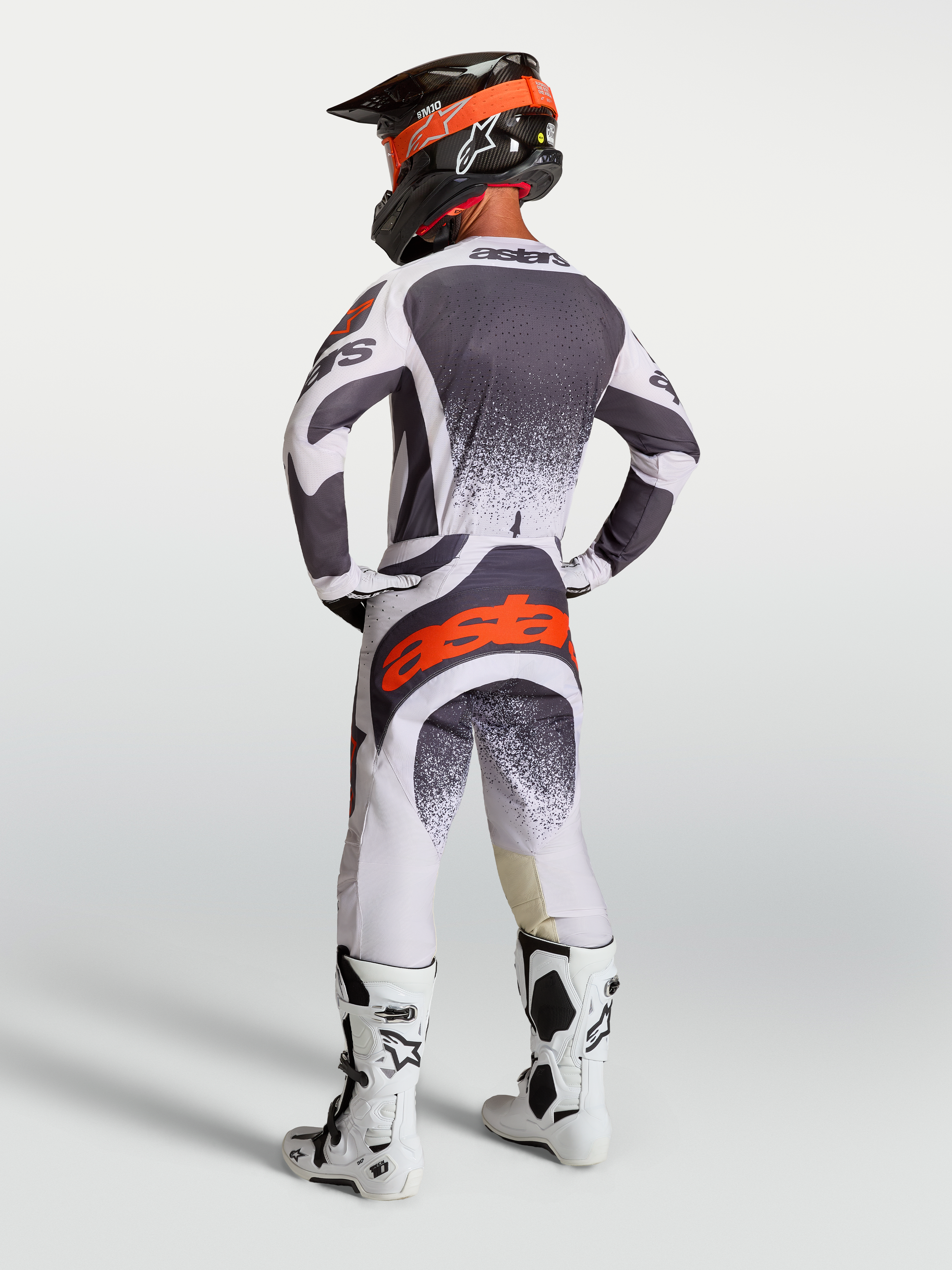 Alpinestars Techstar Swan, camisola e calças de motocross para homem, cinzento e branco com pormenores vermelho fluo, vista traseira no modelo