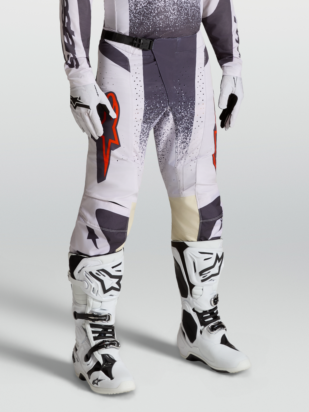 Calças Techstar Swan Alpinestars, calças de motocross para homem, lilás claro e cinzento escuro com detalhes em vermelho fluo, modelo equipado com luvas e botas.