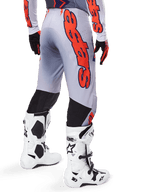 Alpinestars 2025 Supertech Lipan Pants, Motocross Pants, Gray and Orange Fluo, worn with matching jersey and white boots, back view featuring large orange Alpinestars graphic branding, black stretch panels, professional dirt bike racing gear