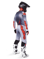 Motocross rider from the back wearing Alpinestars 2025 Supertech Lipan Pants in Gray and Orange Fluo, matching long-sleeve jersey, black helmet, and white and black tech boots, complete professional off-road racing gear.