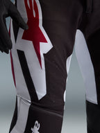 Calças Alpinestars Supertech AFD Vista 2026, calças de motocross, pretas, vermelhas e brancas, grande plano da zona da coxa com um logótipo de estrela grande em vermelho e branco, perfurações feitas a laser para circulação de ar e tecido ripstop elástico durável