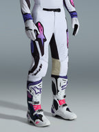 Alpinestars 2026 Supertech AFD Vista Pants, calças de motocross, brancas, roxas e pretas, com um logótipo Astar em degradê rosa e roxo, usadas com botas e luvas de motocross brancas e roxas a condizer, ajuste atlético de corrida com painéis internos nos joelhos em pele bege e detalhes perfurados.