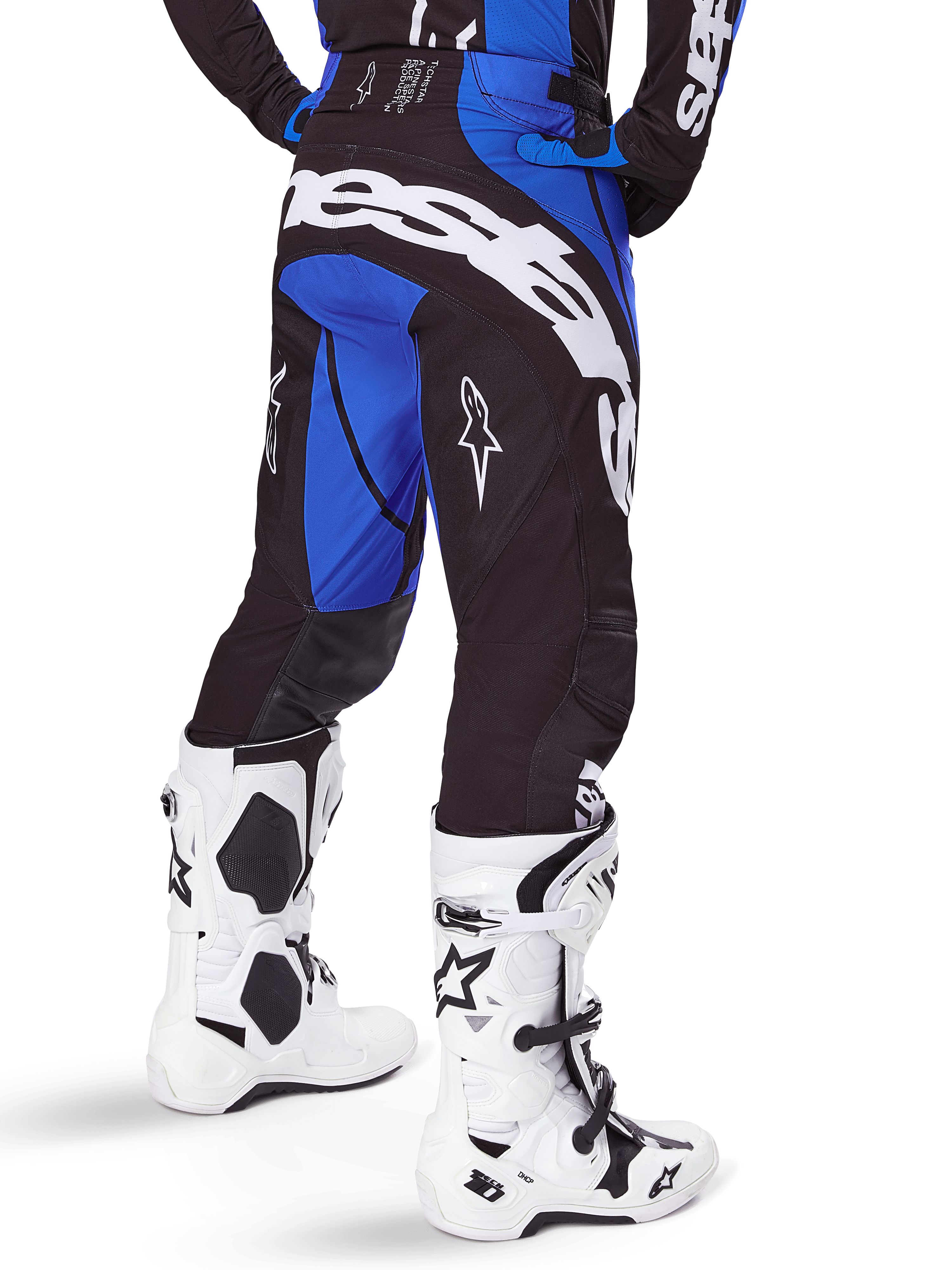 Alpinestars 2025 Techstar Dreem Pants, calças de motocross, pretas e azuis, vista traseira com logótipo Alpinestars em destaque a branco no assento, usadas com botas de motocross brancas e pretas e camisola azul a combinar, corte atlético para corridas todo-o-terreno
