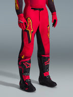 Alpinestars 2026 Supertech Scenz Pants, calças de motocross, vermelhas, pretas e amarelas, com logótipos Alpinestars amarelos e painéis pretos, usadas com camisola vermelha a condizer, luvas vermelhas e botas de motocross pretas