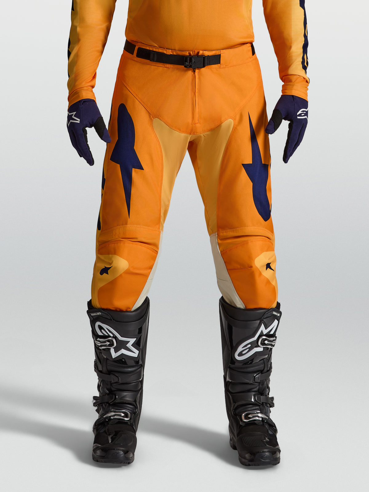 Calças de motocross Alpinestars Racer Amber em laranja e azul escuro, com polifibra 600D e corte de corrida, num modelo.