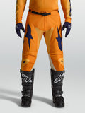 Calças de motocross Alpinestars Racer Amber em laranja e azul escuro, com polifibra 600D e corte de corrida, num modelo.