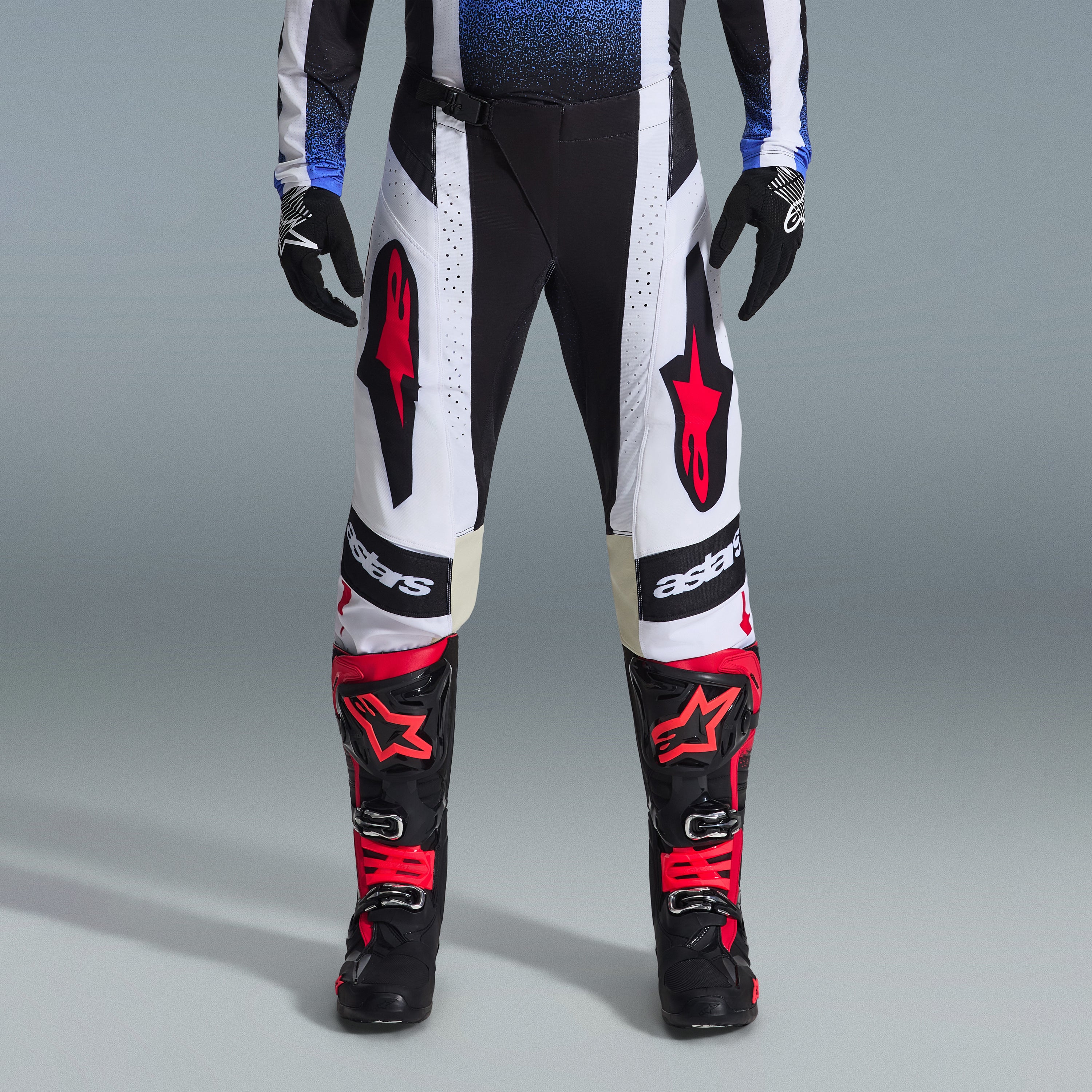 Conjunto de Equipamento Alpinestars Techstar Knif 2026, equipamento de motocross, calças pretas e brancas com grandes logótipos de estrela vermelhos, usadas com botas de corrida pretas e vermelhas e luvas pretas, corte atlético profissional para desempenho em todo-o-terreno