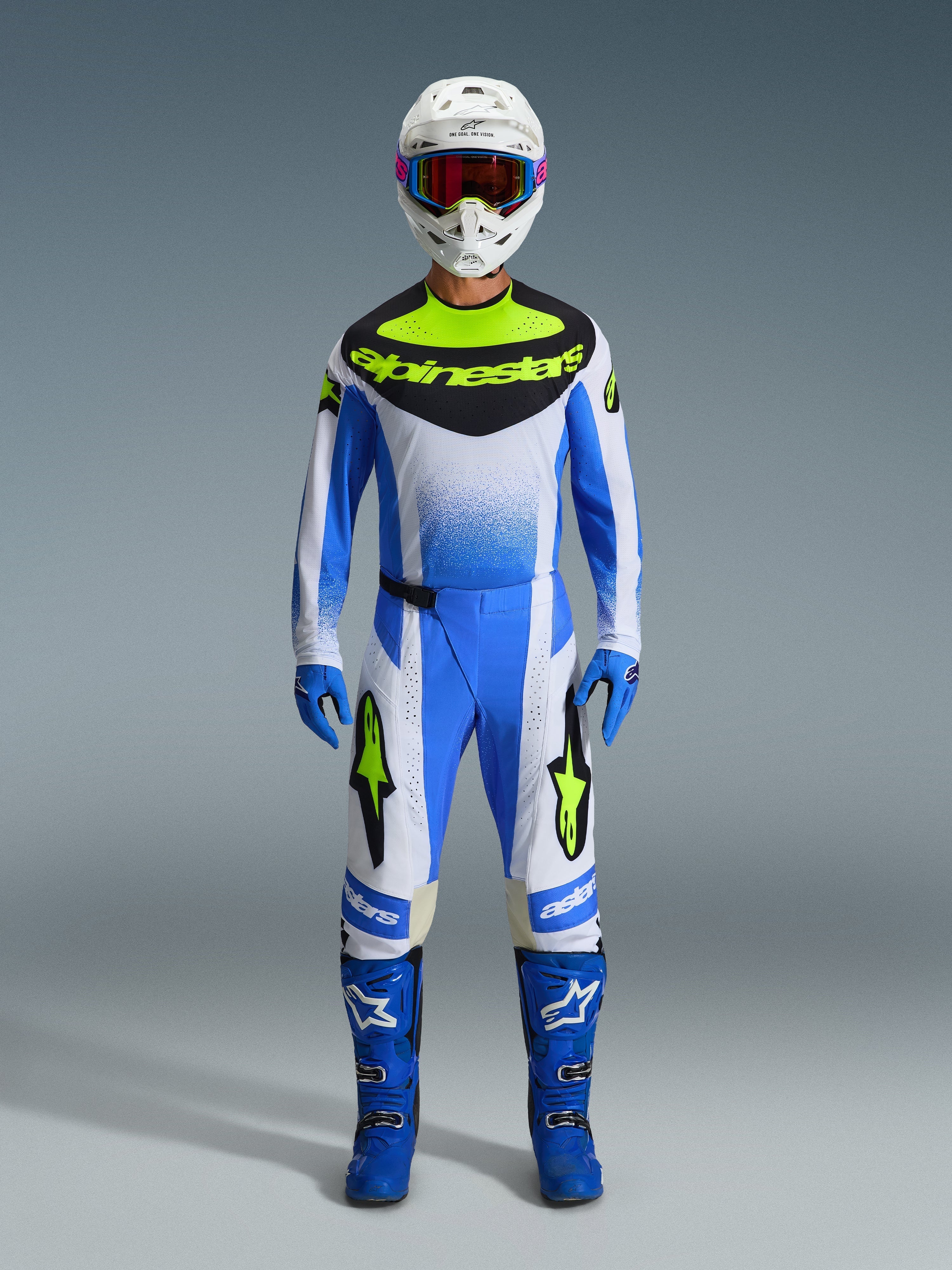 Alpinestars 2026 Techstar Knif Gear Set, conjunto de motocross em azul, branco e amarelo néon, plano de corpo inteiro do piloto a usar camisola e calças a condizer com capacete branco, óculos azuis e botas de corrida azuis, kit de competição off-road coordenado