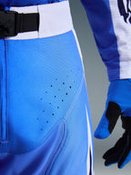 Calças Alpinestars Techstar Knif 2026, calças de motocross, azul UCLA e preto, vista de pormenor da coxa com perfurações cortadas a laser e fivela magnética SX2 na cintura, construção técnica para competições todo-o-terreno