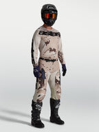 Alpinestars Racer Lone Gear Set, conjunto de camisola e calças de motocross em camuflado bege e castanho com botas pretas.